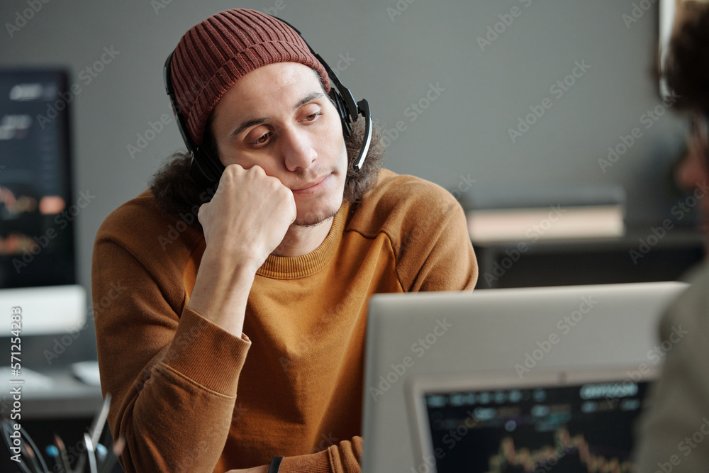Aufkleber young bored operator of call center sitting in front of laptop screen and listening to description o