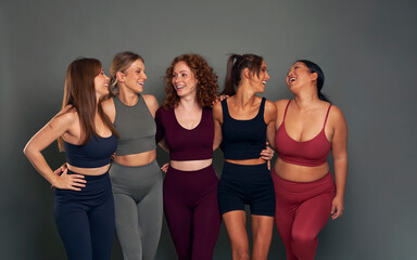 Group of five young women in sports clothes having fun in studio shot