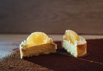 Lemon tartlet on a dark background. Fashionable European dessert with fruit filling.
