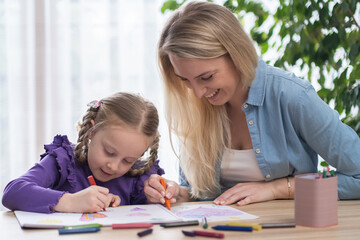 young family spend free time together in living room at home.Mom and little daughter drawing with...