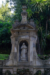 Fototapeta na wymiar A dilapidated statue in a niche in the park with an inscription in Latin 
