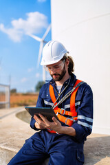 Wind turbine service engineer sit on concrete foundation check tablet plan for maintenance turbine