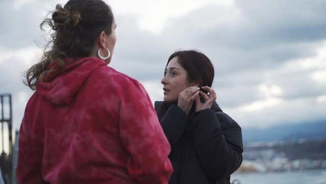 lesbian couple of two caucasian women enjoying a conversation, the sunset and the sea.