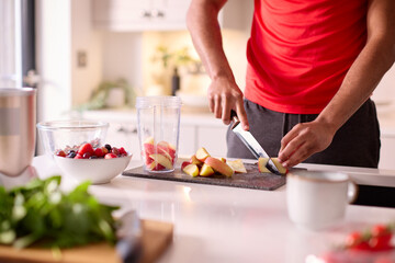Close Up Of Man In Kitchen Wearing Fitness Clothing Blending Fresh Ingredients For Healthy Drink