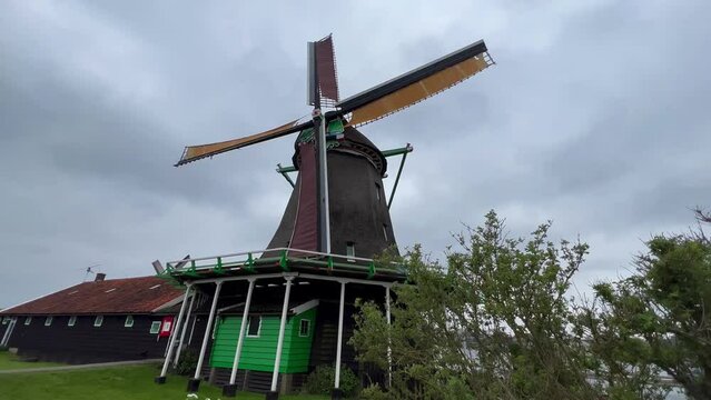 Traditional wooden mills with rotating blades by the river in old town Zaanse Schans, North Holland, Netherlands. May 15, 2022 High quality 4k footage