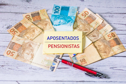 As palavras Aposentados e Pensionistas em Português do Brasil escritas em um pedaço de papel com notas do Real Brasileiro na composição.