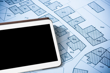 Imaginary cadastral map of territory with buildings and land parcel - concept with a digital tablet with copy space