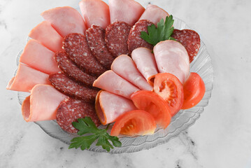 plate with an assortment of boiled, smoked sausage on bright table.