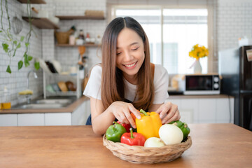Pretty Asian woman preparing healthy breakfast at home in modern and beautiful kitchen, smiling brightly.