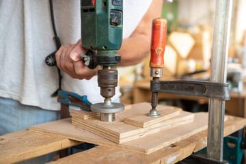 Closeup portrait of unknown unrecognizable man carpenter with drill working in manual and craft work. Making wooden furniture in a small business.