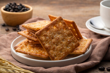 Dry thin crispy sugar crackers in white plate on wooden table