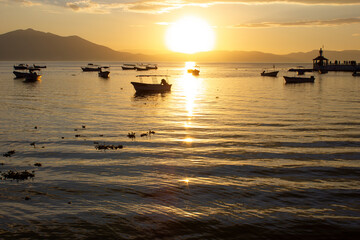 Boats floating on a lake at sunset with a dock in the background