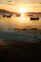 Boats floating on a lake at sunset with two mountains in the background