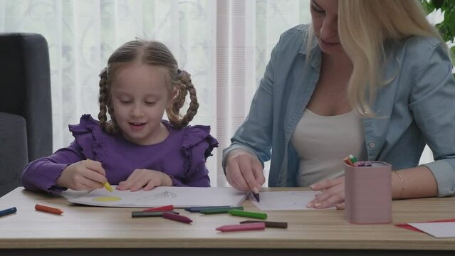 young family spend free time together in living room at home.Mom and little daughter drawing with colorful pencils on paper happy smiling 