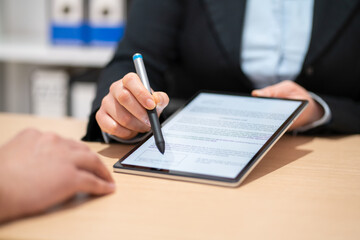 Close up of an executive hands holding a pen with digital tablet and indicating where to sign a...