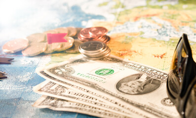 Map with pins marking a travel route. Different travel accessories - money, coins, sunglasses. Selective focus