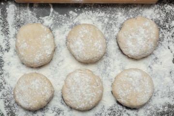 
raw bread dough with flour scattered on a black table