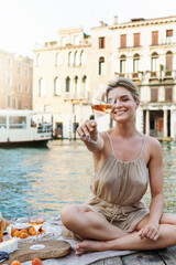 Lovely young woman picturesque picnic on the wooden gondola dock with rose wine, fruits and snack on wooden pier © blackday