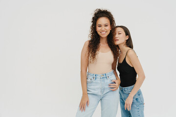 Two young multinational girls posing isolated over white wall
