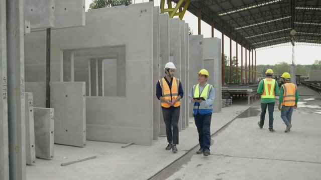 Engineers are inspecting work inside a precast concrete factory producing house walls, columns or beams.
