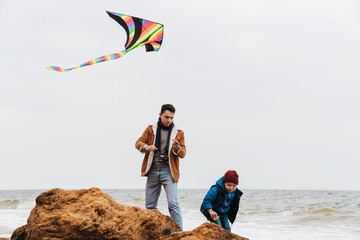 Father and his son playing with kite on the beach