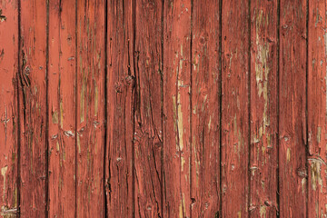 Detail of antique wooden door in red tones, with lots of texture and pickled paint.