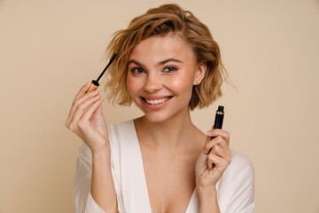Obraz premium Young cheerful woman posing with mascara isolated