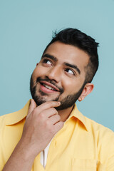 Pensive indian man touching his chin while posing isolated over blue background