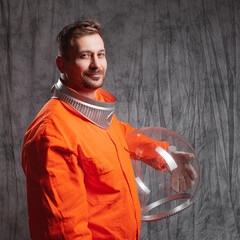 Retro futuristic astronaut in a spacesuit with a bright orange jumpsuit and a spherical glass helmet