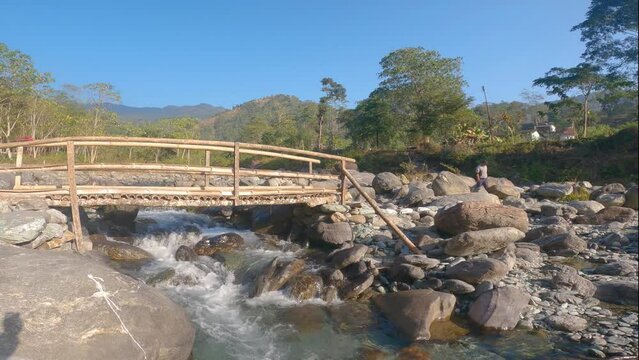 8th December, 2023, Kurseong, West Bengal, India: Beautiful landscape of mountain river coming through rocks and a wooden bridge over the river.