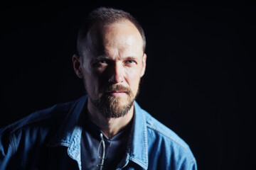 Concentraited middle age man in denim shirt looking squinting at camera