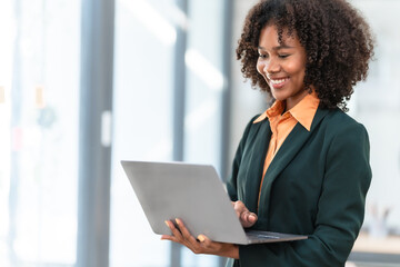 Using laptop computer, Young pretty african american business woman bookkeepers working with...