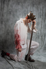 The hero of the tragedy, the mad king in a bloody shirt with a sword in his hands, suffers on his knees