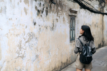 Fototapeta na wymiar Young Asian woman backpack traveler using digital compact camera, enjoying street cultural local place and smile. Traveler checking out side streets. Journey trip lifestyle, world travel explorer