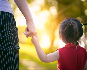 parent holding the child's hand with nature background