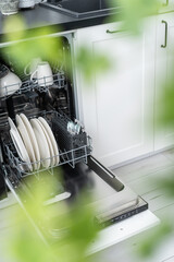 open dishwasher with clean plates, cups and cutlery