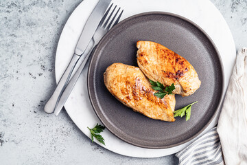 Roasted chicken breast on  plate on grey background, top view