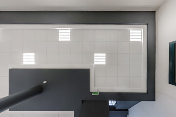 cassette stretched or suspended ceiling with square halogen spots lamps and drywall construction in empty room in house or office with column. Looking up view
