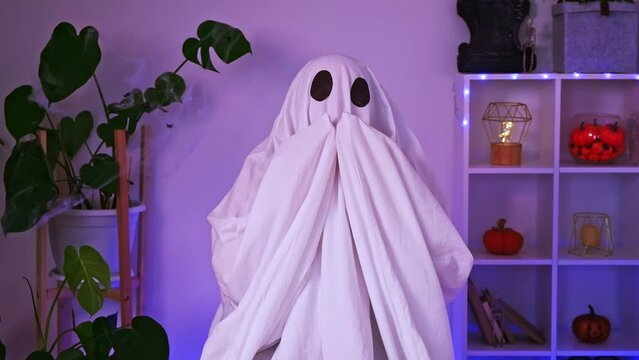 The ghost expresses emotions by blowing a kiss, scratching his head, the back of his head, surprise, love, fooling around. Halloween concept. Neon light in the background