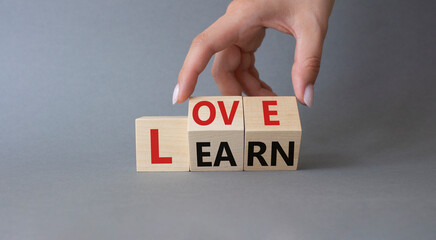 Love and Learn symbol. Businessman hand turns wooden cubes and changes word Learn to Love. Beautiful grey background. Lifestyle and Love and Learn concept. Copy space.