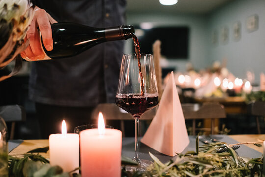 Kellner schenkt Rotwein in ein Weinglas