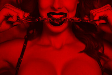Sexy woman bite handcuffs closeup black and white with red