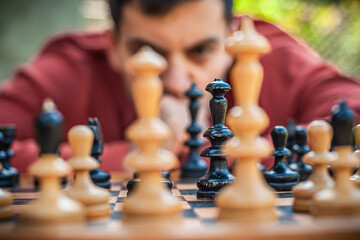 Close up. Man playing chess, thinking about next move, spring day, outside.