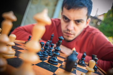 Close up. Man playing chess, thinking about next move, spring day, outside.