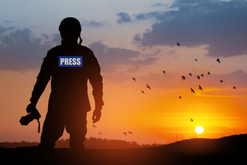 Photojournalist silhouette documenting war or conflict. Photojournalist at sunset. War, army, technology and journalist work concept. - obrazy, fototapety, plakaty