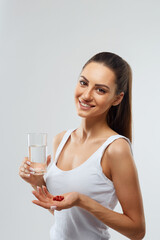 Portrait Of Beautiful Smiling Young Woman With Vitamin Pills. Happy Girl Holding Medications And Glass Of Fresh Water In Hand.
