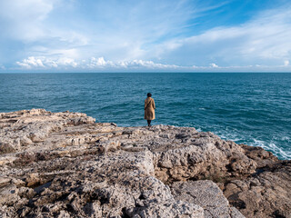 Woman isolated on the rocks looking at the sea in winter season