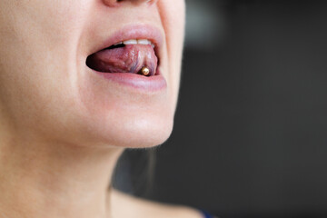 Woman shows piercing on her tongue. Closeup, selective focus.