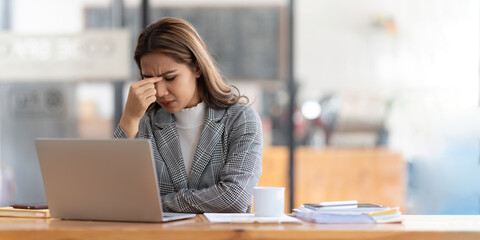 Young businesswoman working on laptop stressed has a headache and thinks hard from work at the office