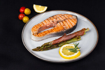 Fresh cooked delicious salmon steak with asparagus, spices and herbs baked on a grill. Healthy seafood food.